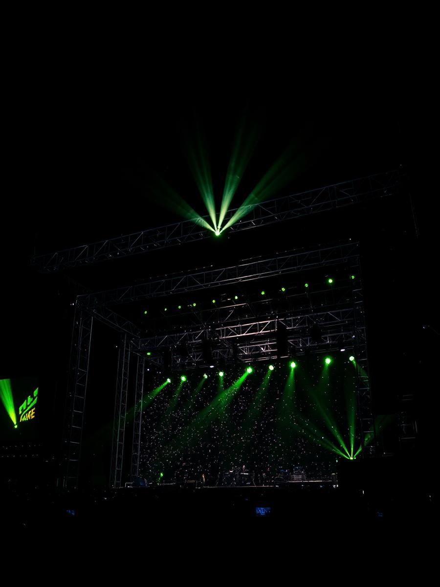 Estrutura de palco de festival iluminada por feixes verdes