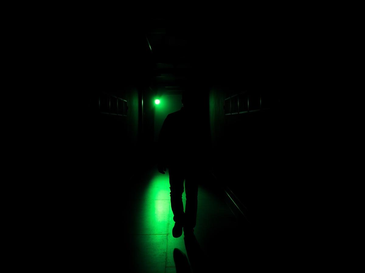 Silhueta de artista nos bastidores em corredor iluminado de verde